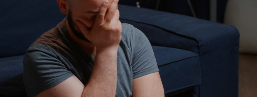 An image of a distressed gay man, showing a symptom of PTSD.