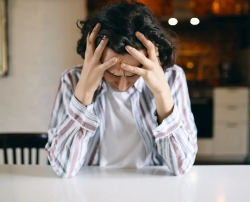 Queer person with a distressed expression, conveying feelings of anxiety, trauma, and rejection.