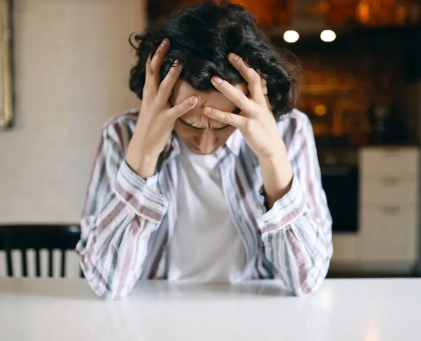 Queer person with a distressed expression, conveying feelings of anxiety, trauma, and rejection.