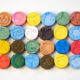 A variety of colorful MDMA (Molly) tablets arranged on a white surface, representing the different forms in which the drug is consumed.