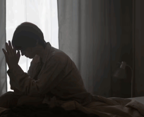 A lesbian in their bed, looking anxious and depressed.