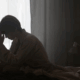 A lesbian in their bed, looking anxious and depressed.