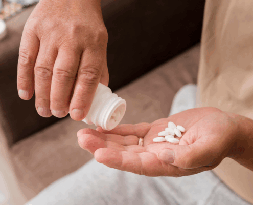 An image of a person's hand pouring white desoxyn tablets into his palm from a medicine container.