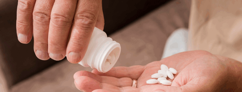 An image of a person's hand pouring white desoxyn tablets into his palm from a medicine container.