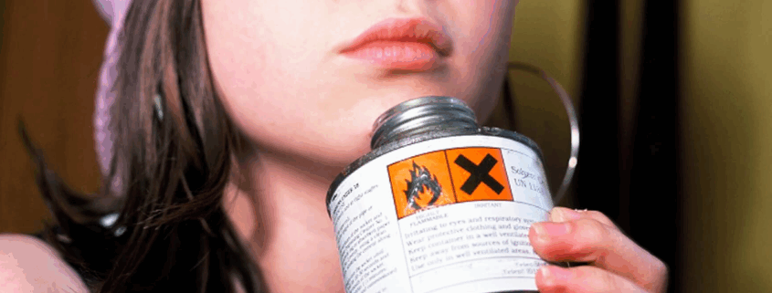 A young queer woman huffing glue through their nose