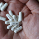 A hand with white gabapentin capsules.