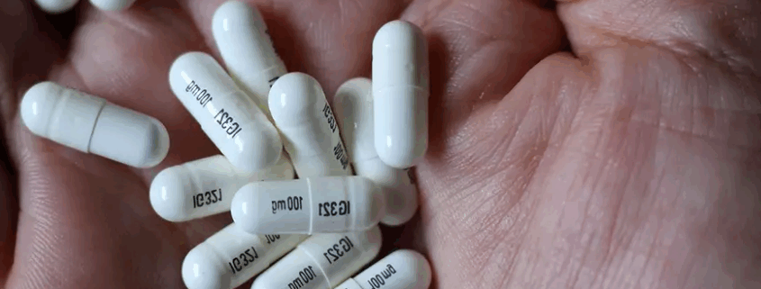 A hand with white gabapentin capsules.