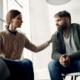 A female therapist comforting a gay person in a trauma-informed addiction treatment center.